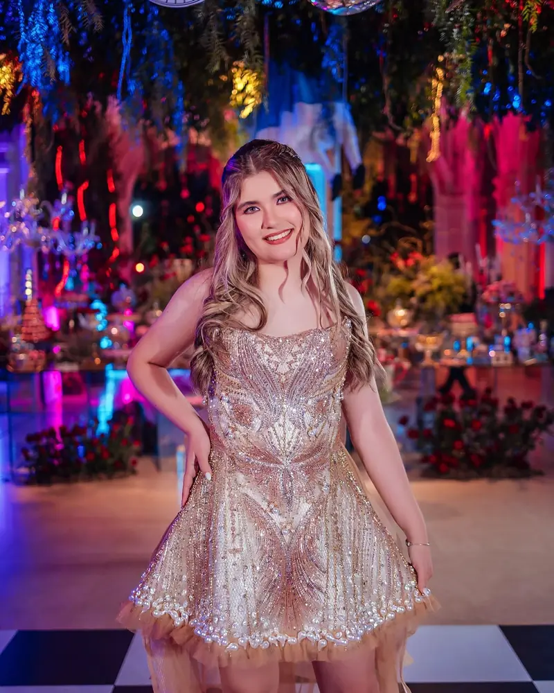 Quinceañera con vestido brillante dorado en una fiesta de colores