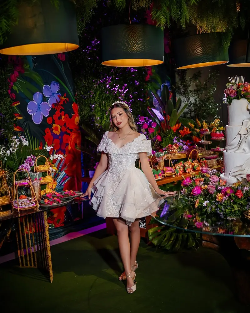 Quinceañera posando junto a la mesa de dulces en su fiesta
