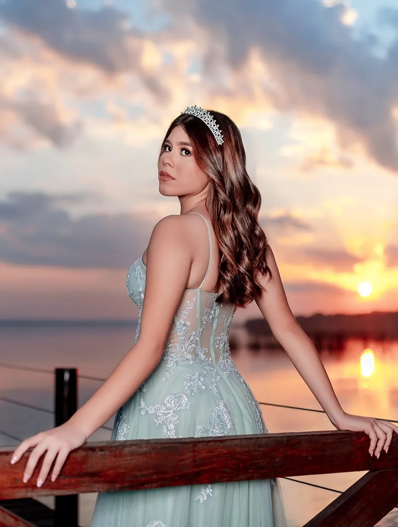 Quinceañera de espaldas en un muelle con el sol bajando