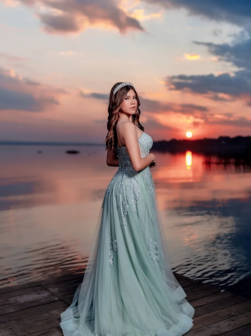 Quinceañera con vestido celeste frente al lago al atardecer