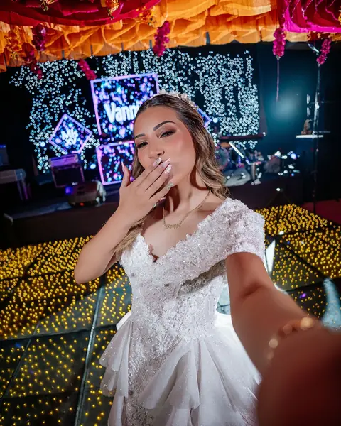 Quinceañera sonriendo en su fiesta, con luces de colores