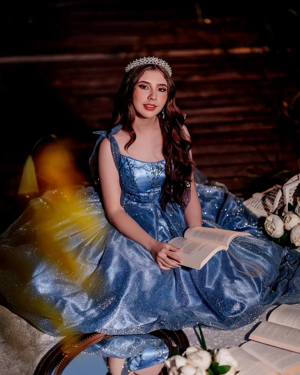 Quinceañera con vestido azul en un jardín, de noche